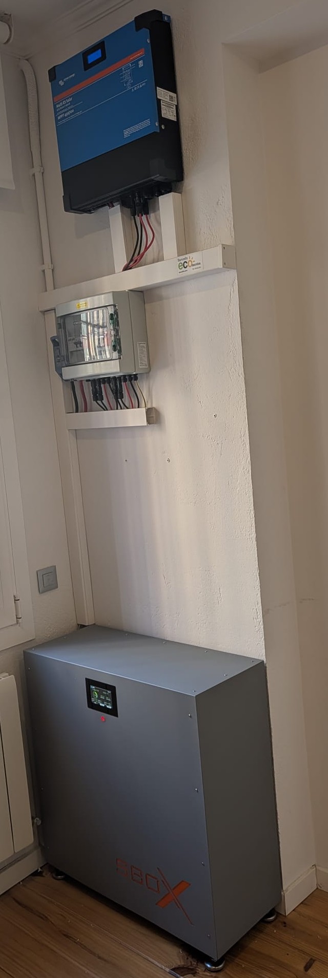 Instal·lació domèstica en una paret interior: moble SolarBox SBx 30 amb un mòdul LFP de 15 kWh, inversor Victron Multi RS Solar a dalt i caixa de proteccions al mig